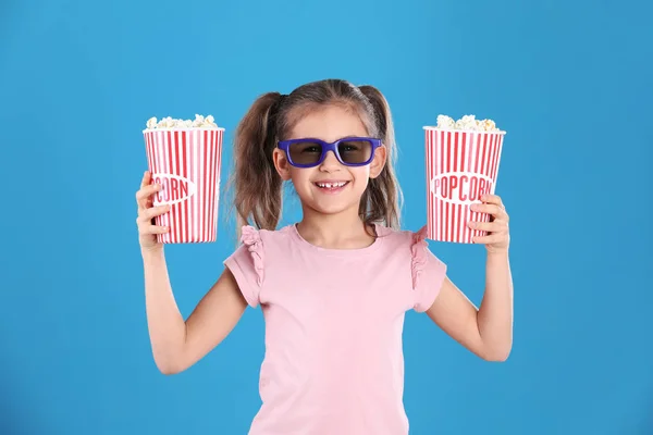 Linda niña con palomitas de maíz y gafas en el fondo de color —  Fotos de Stock