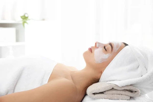 Jolie femme avec masque sur le visage dans le salon de spa — Photo