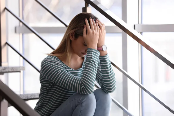Эмоциональная девочка-подросток сидит на лестнице в помещении — стоковое фото