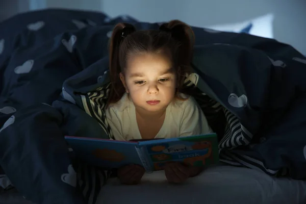 Krásná dívka čtení knížky v posteli v noci. Pohádka — Stock fotografie