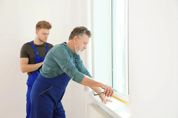 Службовці вимірюють вікно для установки в приміщенні — стокове фото