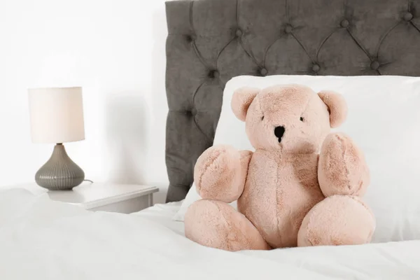 Милий плюшевий ведмідь сидить на ліжку в приміщенні. Простір для тексту — стокове фото