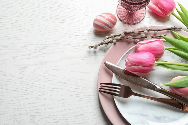 Festive Easter table setting with flowers on wooden background, above view. Space for text — Stock Photo, Image