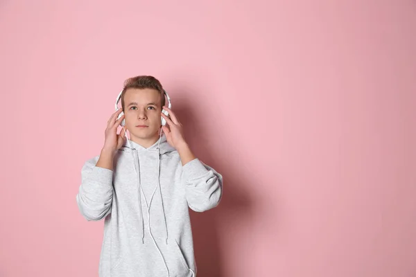 Adolescent garçon écoute de la musique avec casque sur fond de couleur, espace pour texte — Photo