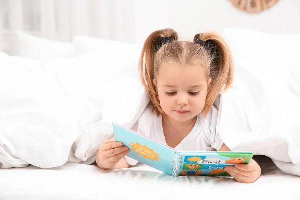Όμορφο κοριτσάκι με το βιβλίο στο κρεβάτι στο σπίτι. Πρόγραμμα ύπνου — Φωτογραφία Αρχείου