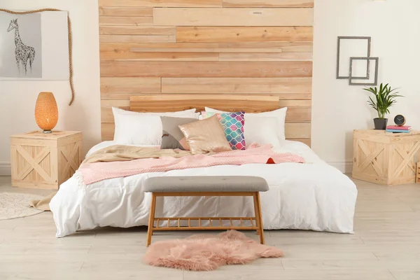 Стильный интерьер комнаты с удобной кроватью возле деревянной стены — стоковое фото