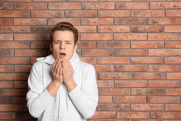 Adolescente que sufre de tos cerca de la pared de ladrillo. Espacio para texto —  Fotos de Stock