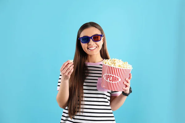 Young woman with 3D glasses and tasty popcorn on color background — Stock Photo, Image