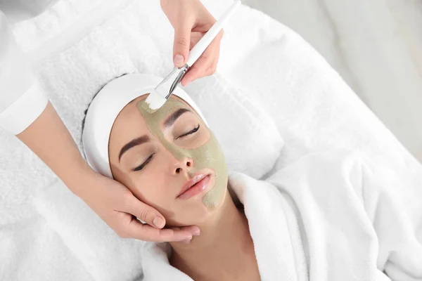 Cosmetologist aplicando máscara no rosto do cliente no salão de spa, vista acima — Fotografia de Stock