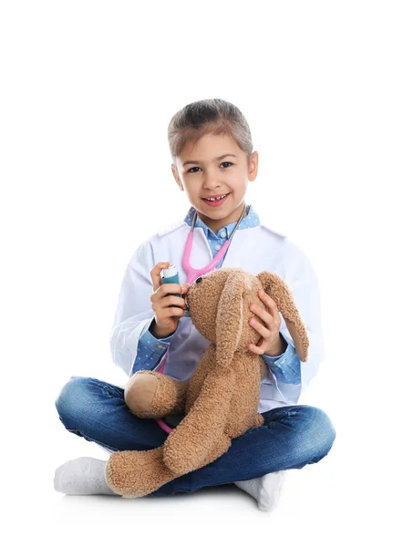 Lindo niño jugando doctor con peluche juguete sobre fondo blanco —  Fotos de Stock