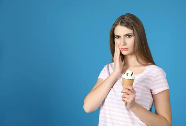 Emotional young woman with sensitive teeth and ice cream on color background. Space for text — Stock Photo, Image