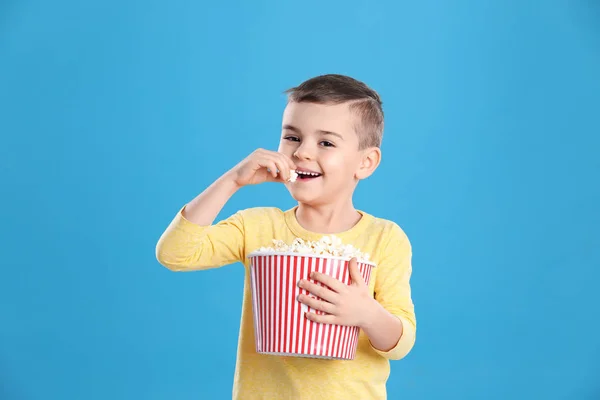 Menino bonito com pipoca no fundo de cor — Fotografia de Stock