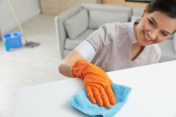 Young maid dusting furniture with rag in hotel room — Stock Photo, Image