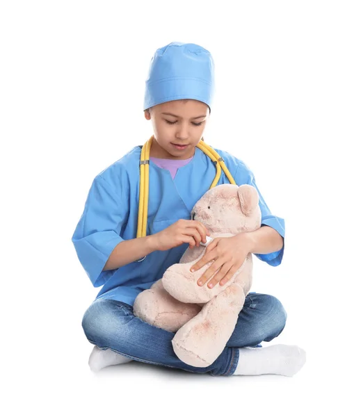 Bonito criança brincando médico com brinquedo de pelúcia no fundo branco — Fotografia de Stock