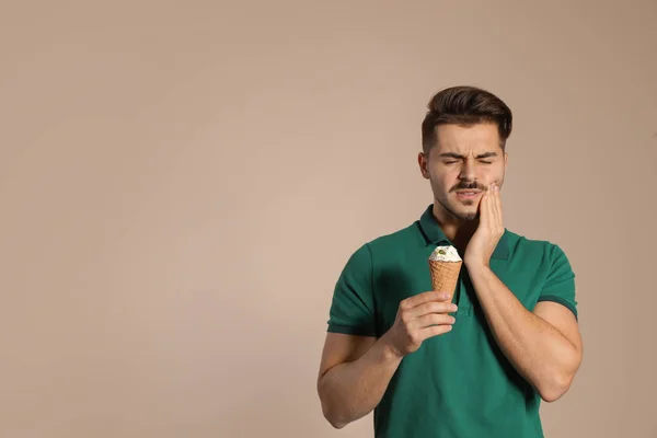 Emocionální mladý muž s citlivými zuby a zmrzliny na barvu pozadí. Prostor pro text — Stock fotografie