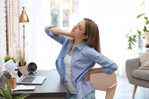 Fiatal nő szenved hátfájás az irodában — Stock Fotó