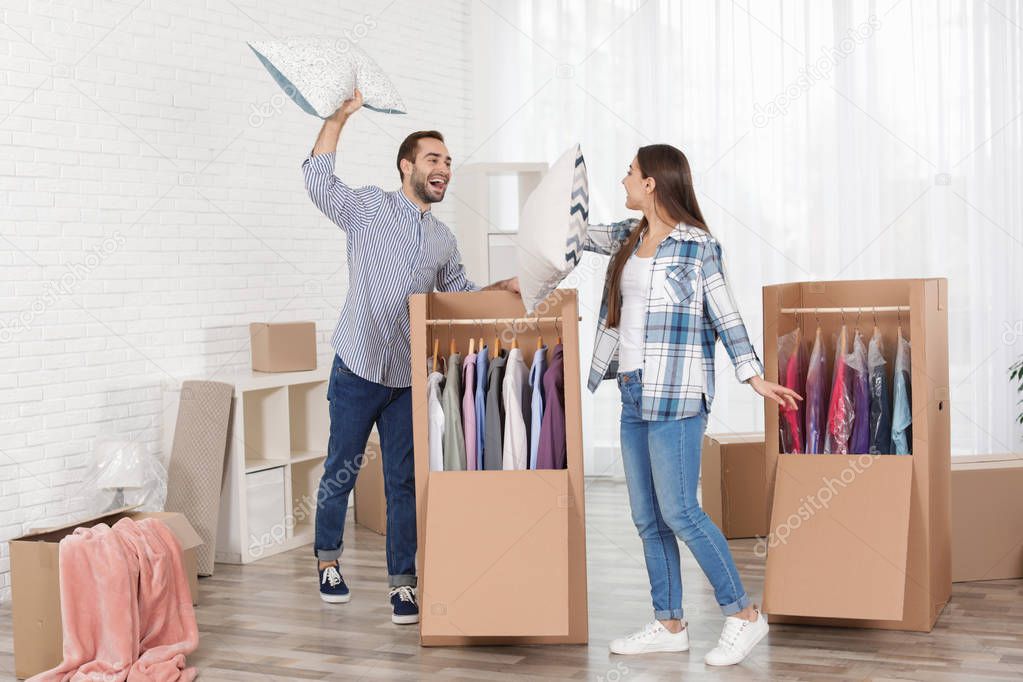 Young couple having pillow fight near wardrobe boxes at home