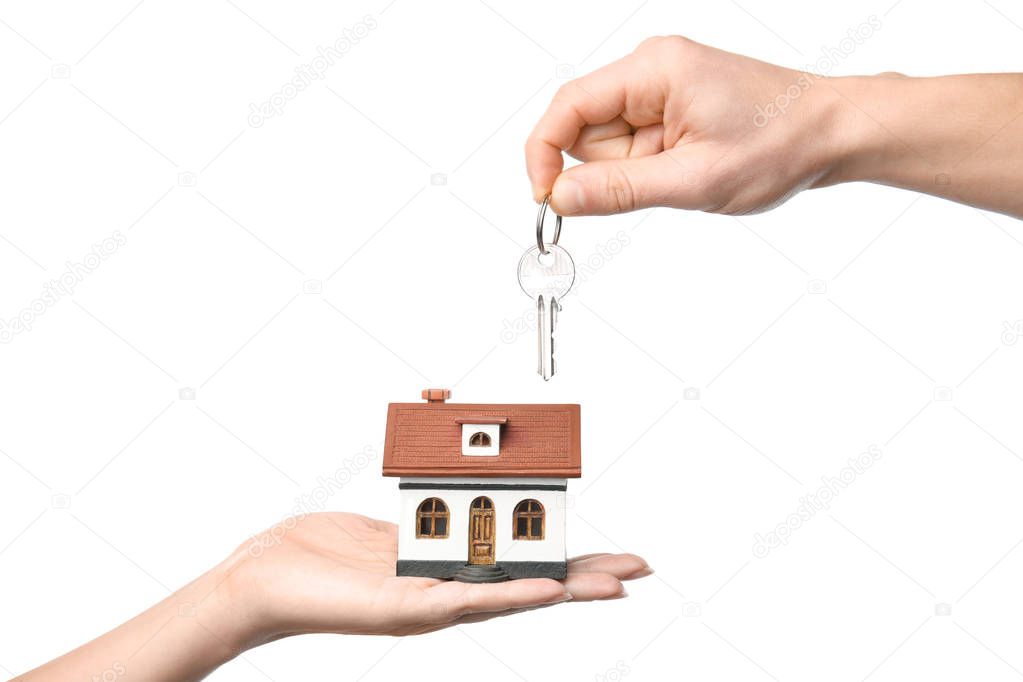 People holding key and house model on white background, closeup