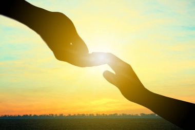 Kadın eli için açık havada, güneş doğarken closeup ulaşan adam. Kavram