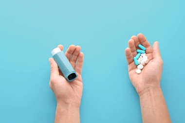 Astım inhaler ve hap mavi arka plan, üstten görünüm tutan adam