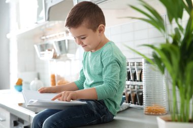 Sevimli küçük çocuk okuma kitabı evde mutfak