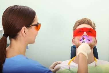 Profesyonel diş hekimi modern klinik hasta ile çalışma. Diş beyazlatma