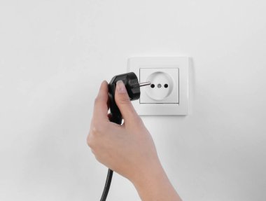 Fişi elektrik prizine takın beyaz zemin üzerine, closeup koyarak kadın. Elektrik teknisyen ekipmanları