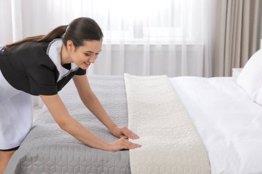Genç hizmetçi otel odasında yatak yapma