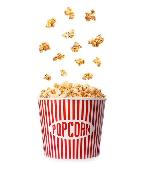 Delicious caramel popcorn falling into carton bucket on white background — Stock Photo, Image