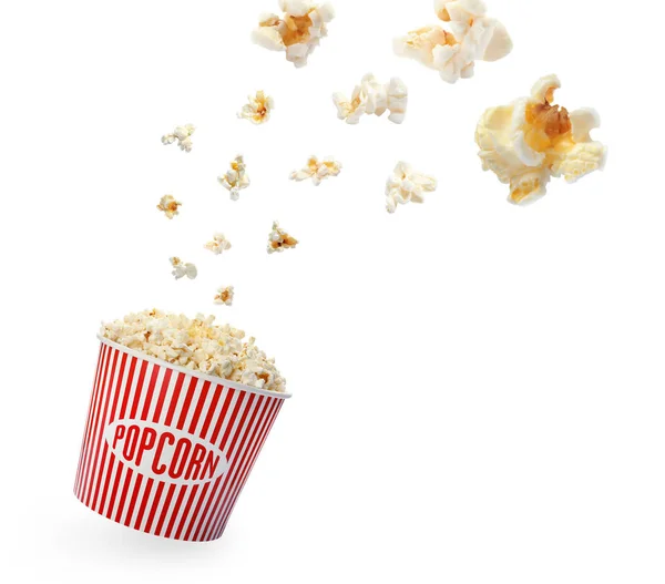 Delicious salty popcorn falling into carton bucket on white background — Stock Photo, Image