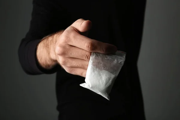 Narcotraficante sosteniendo bolsa con cocaína sobre fondo oscuro, primer plano —  Fotos de Stock