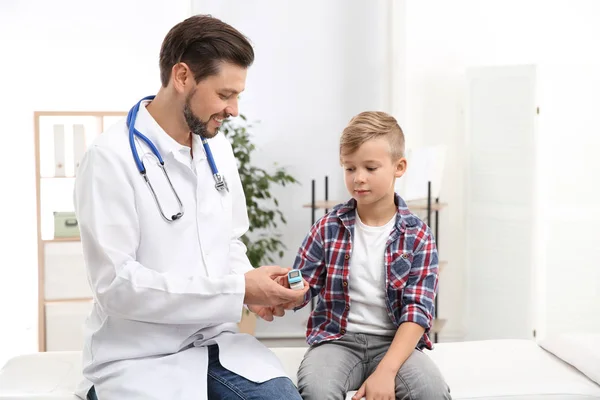 Лікар перевіряє пульс маленького хлопчика за допомогою медичного пристрою в лікарні — стокове фото