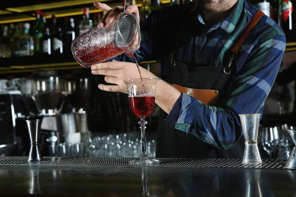 Barman derramando coquetel através de filtro em vidro no balcão no pub, close-up — Fotografia de Stock