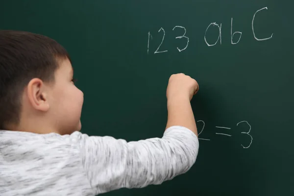 Kleines Kind schreibt Mathe-Summe auf Tafel — Stockfoto