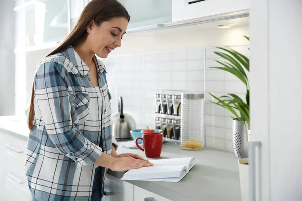 Hermosa joven con taza de libro de lectura de café en casa — Foto de Stock