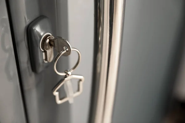 Chave com bugiganga em forma de casa na fechadura da porta, close-up. Espaço para texto — Fotografia de Stock