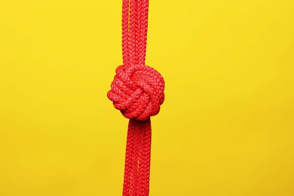 Red rope with knot on color background — Stock Photo, Image