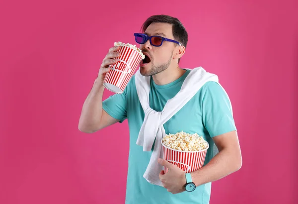 Человек в 3D очках ест вкусный попкорн на цветном фоне — стоковое фото