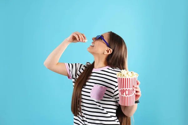 Mujer joven con gafas 3D comiendo palomitas de maíz sabrosas en el fondo de color —  Fotos de Stock
