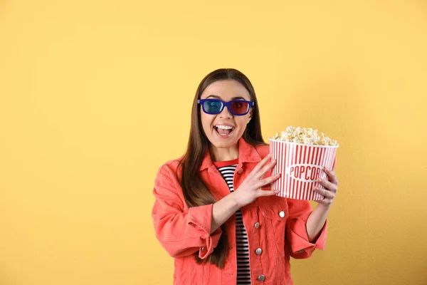 Emotionale Frau mit 3D-Gläsern und leckerem Popcorn auf farbigem Hintergrund — Stockfoto