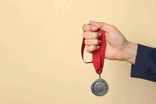 Woman holding golden medal on color background, closeup. Space for text — Stock Photo, Image