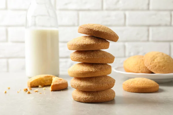 Stack of Danish butter cookies and milk on table against brick wall — Stock Photo, Image