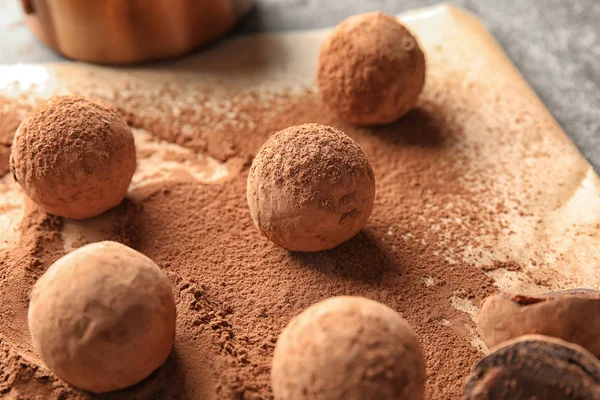 Sweet chocolate truffles powdered with cacao on parchment paper