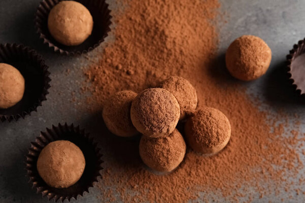 Tasty chocolate truffles powdered with cocoa on grey background, top view
