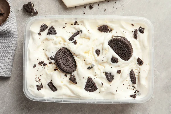 Container of ice cream and chocolate cookies on grey background, top view — Stock Photo, Image