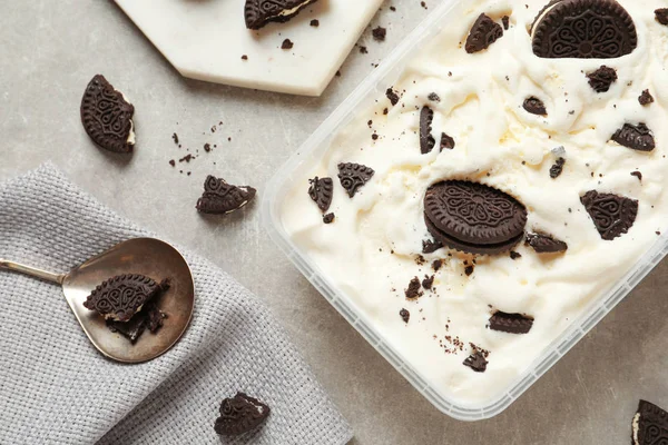 Flat lay composition with container of ice cream and chocolate cookies on grey background — Stock Photo, Image