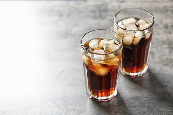 Vasos de cola con hielo sobre fondo gris, espacio para texto — Foto de Stock