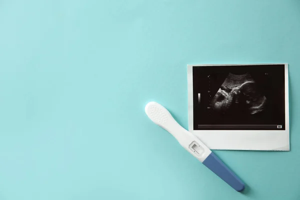 Ультразвук изображения ребенка и тест на беременность на цветном фоне, вид сверху с пространством для текста — стоковое фото