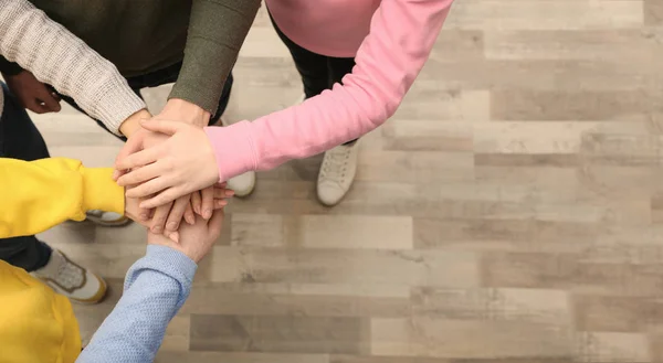 Grupo de pessoas segurando as mãos juntas dentro de casa, vista superior. Espaço para texto — Fotografia de Stock