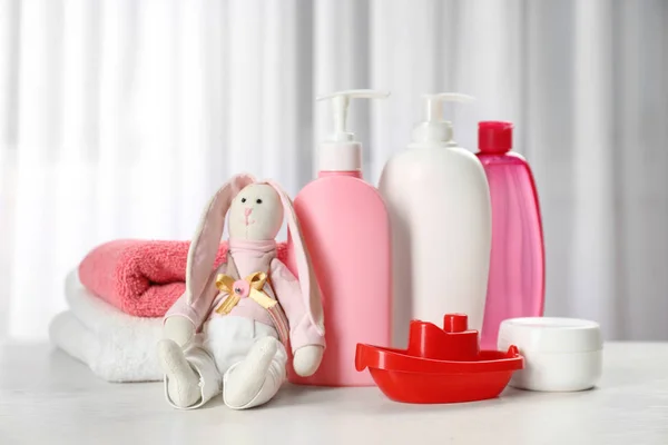 Kosmetiska babyprodukter, leksaker och handdukar på bord inomhus — Stockfoto